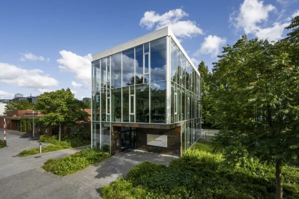 Modern glazen kantoorgebouw van Biometrisch aan de Fred. Roeskestraat, omgeven door groen en bomen.